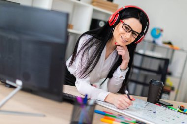 Genç bir kız kulaklık tablo anlamına gelir ve bir işaretleyici manyetik bir tahtaya çizer.