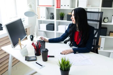 Bilgisayar ve ofis belgeleri ile masada çalışan güzel bir genç kız.