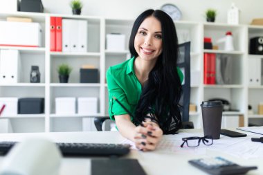 Genç bir kız ofis masada oturur ve onun elinde kalem tutan.