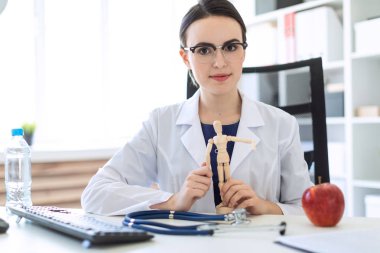 Beyaz bir elbise içinde güzel bir genç kız bir masada oturan ve bir adam ahşap bir rakam onun elinde tutan.
