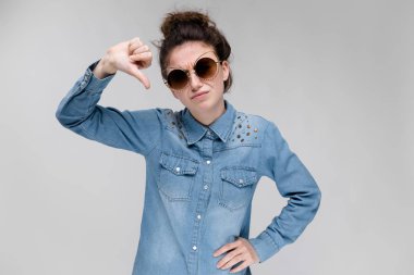 Siyah gözlüklü genç esmer kız. Kedi gözlük. Saç bir topuz toplanır. Kızı sevmemek gösterir.