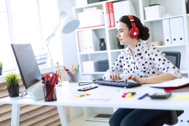 Beyaz bir bluz geometrik desen ve mavi kot pantolon güzel genç kız. Siyah saçlı ve güzel makyaj kız. Çekici bir genç kız parlak bir ofiste çalışıyor. alan derinliği ile fotoğraf.