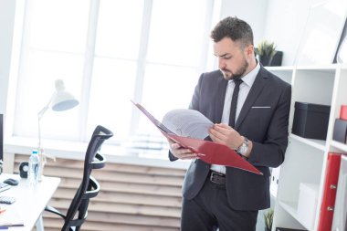 Ofis ve belgeler klasörüyle ile verilirse rafa yakın duran adam.