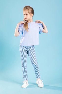 Mavi arka planda mavi elbiseli güzel bir kızın tam boy portresi..