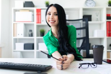 Genç bir kız ofis masada oturur ve onun elinde kalem tutan.