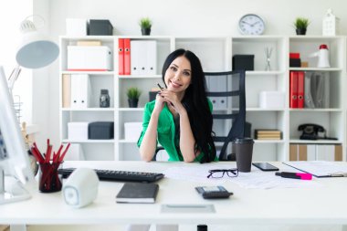 Genç bir kız ofis masada oturur ve onun elinde kalem tutan.