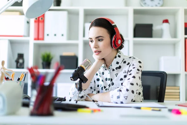 Kulaklık ve mikrofon ofis masada oturan ve konuşmak güzel genç kız.