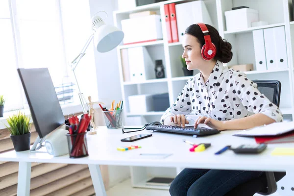 Beyaz bir bluz geometrik desen ve mavi kot pantolon güzel genç kız. Siyah saçlı ve güzel makyaj kız. Çekici bir genç kız parlak bir ofiste çalışıyor. alan derinliği ile fotoğraf.