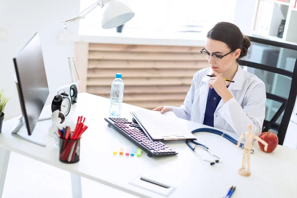 Beyaz bir elbise içinde güzel bir genç kız bir bilgisayar masası belgeler ve bir kalem ile onun elinde oturuyor.