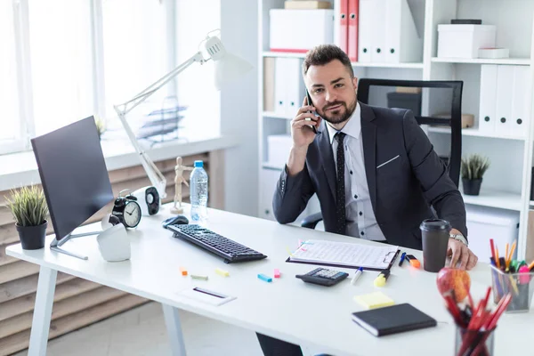 Bir adam ofiste masa başında oturan, telefonda konuşurken ve düz arıyorsunuz.