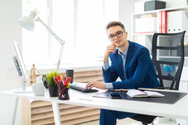 Ofiste masada oturan ve bilgisayarda çalışan genç adam.