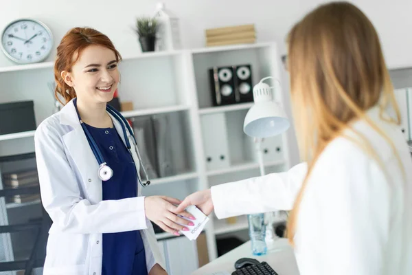 En vacker ung flicka i en vit klädnad är står nära en dator skrivbord på kontoret och kommunicera med samtalspartnern. Samtalspartner skakar flickor handen och händer henne pengarna. — Stockfoto