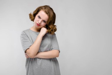 Gri T-shirt gri bir arka plan üzerine sevimli genç kız. Kız kafasını onun tarafına eğik.