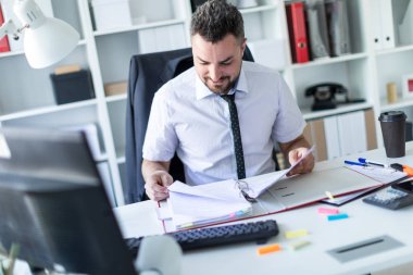 Bir adam ofiste oturan ve belgeleriyle çalışma.