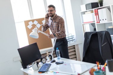 Bir adam ofis pencerenin yanında duran ve telefonda konuşurken.