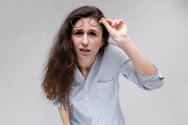 Gözlüklü genç esmer kız. Gözlüklerini büyümüş.