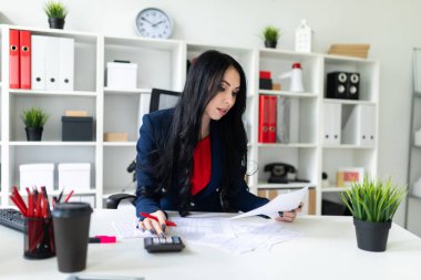 Hesap makinesi ve Office belgeleri ile masada çalışan güzel bir genç kız