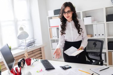 Güzel bir genç kız bir ofis masası anlamına gelir ve bir kalem ve defter elinde tutar. Kız müzakere.