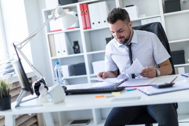 Bir adam ofiste masada oturan ve belgeleriyle çalışma.