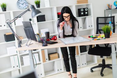 Genç bir kız bir bilgisayar masası duruyor ve bir işaretleyici manyetik bir tahtaya çizer.