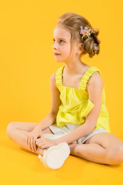 Μια έφηβη κοπέλα κάθεται σε κίτρινο φόντο. — Φωτογραφία Αρχείου
