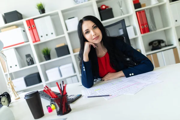 Güzel genç kız ofiste belgelerle çalışma. Masanın üstünde kağıt ve bir kalem vardır.