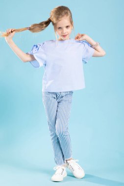 Mavi arka planda mavi elbiseli güzel bir kızın tam boy portresi..