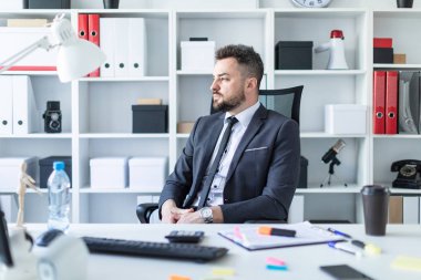 Bir adam masada ofiste bir sandalyede oturuyor.