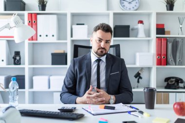 Bir adam masada ofiste bir sandalyede oturuyor.
