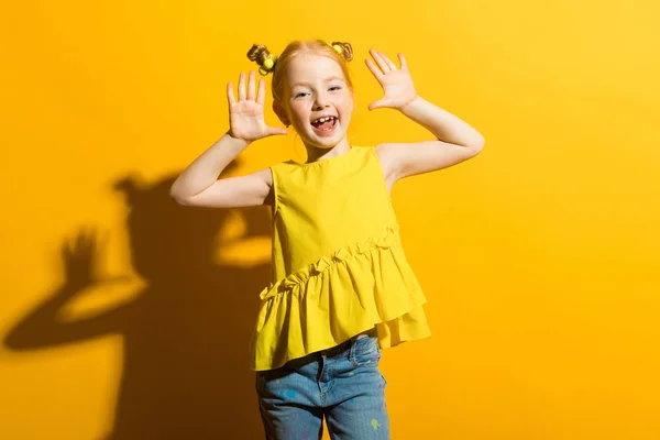 Portrait of a beautiful girl in a yellow blouse and blue jeans.