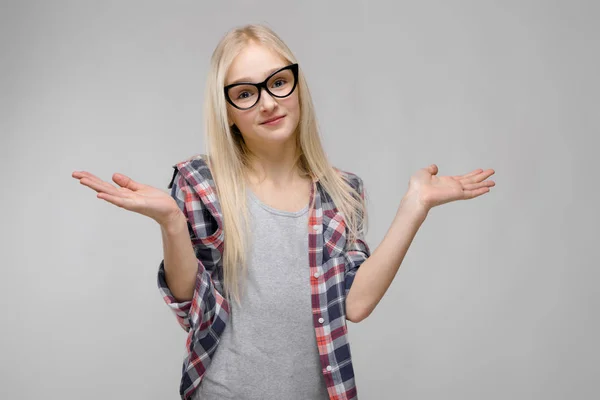Beautiful teen girl with long hair and wearing glasses. A teenage girl in a plaid shirt and a gray T-shirt. A teenager girl smiles and spreads her arms out to the sides — Stock Photo, Image