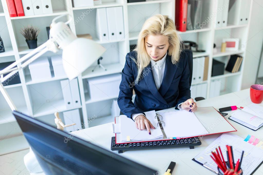 Young girl sitting at desk in office and working with documents.