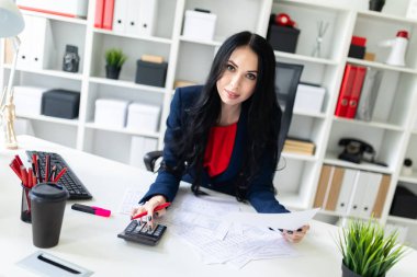 Hesap makinesi ve Office belgeleri ile masada çalışan güzel bir genç kız