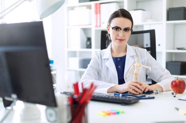 Beyaz bir elbise içinde güzel bir genç kız bir masada oturan ve bir adam ahşap bir rakam onun elinde tutan.