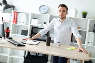 Genç bir adam tablo yakınındaki ofiste elleri üzerinde döşeme standları.