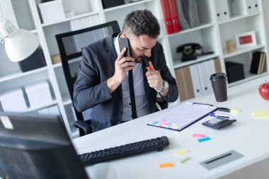 Bir adam ofiste masa başında oturan, telefonda konuşurken ve dudaklarını bir marekker holding.