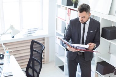 Ofis ve belgeler klasörüyle ile verilirse rafa yakın duran adam.