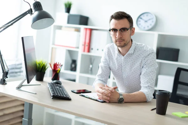 Молодой человек в очках стоит рядом со столом в офисе . — стоковое фото