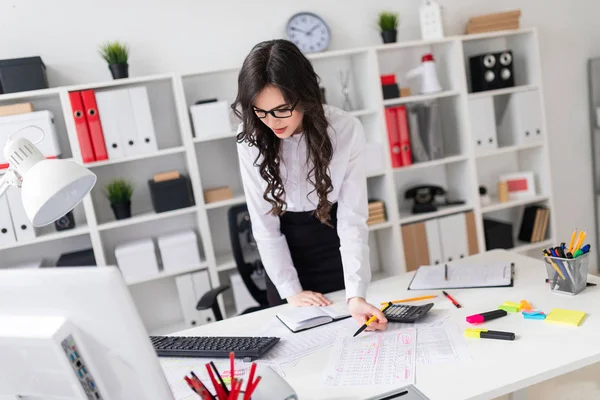 Güzel bir genç kız bir ofis masası üzerinde eğri duruyor, onun elinde bir kalem tutan ve günlüğü görünüyor.