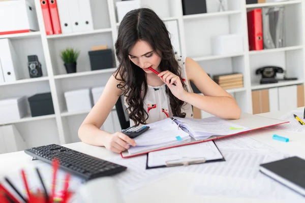 Güzel bir genç kız bir bardak kahve tablo ofiste bir sandalyede oturup ile düzenliyor.