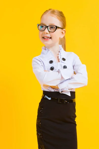 Mädchen mit roten Haaren auf gelbem Hintergrund. ein charmantes Mädchen mit durchsichtiger Brille verschränkte die Arme über der Brust. — Stockfoto