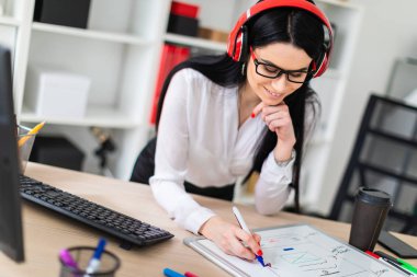 Genç bir kız kulaklık tablo anlamına gelir ve bir işaretleyici manyetik bir tahtaya çizer.