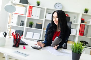 Güzel bir genç kız ile hesap makinesi, bir yandan onun ikinci el tutan bir bardak kahve masada ofiste ile sayar.