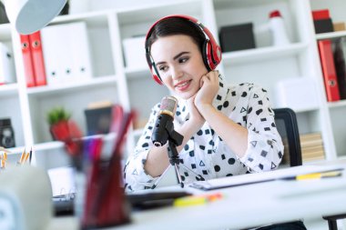 Kulaklık ve mikrofon ofis masada oturan ve konuşmak güzel genç kız.