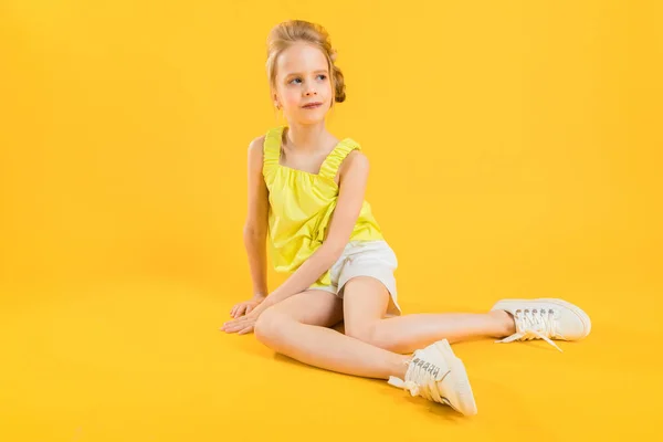 Egy tizenéves lány ül a sárga háttér. — Stock Fotó