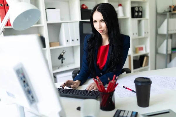 Krásná mladá dívka pracující s počítačem a dokumenty v kanceláři na stole. — Stock fotografie