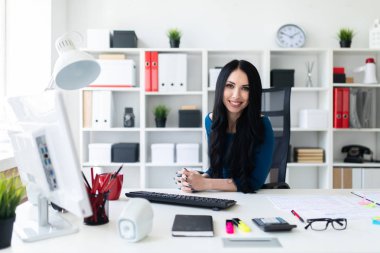 Genç bir kız masada ofisinde oturuyor.