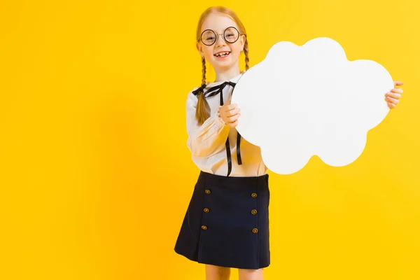 Mädchen mit roten Zöpfen auf gelbem Hintergrund. ein charmantes Mädchen mit runder durchsichtiger Brille hält eine weiße Wolke in ihren Händen. — Stockfoto