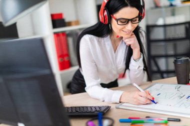 Genç bir kız kulaklık tablo anlamına gelir ve bir işaretleyici manyetik bir tahtaya çizer.