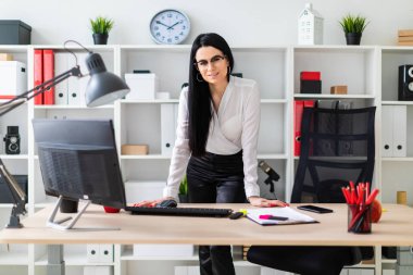 Genç bir kız bir bilgisayar masası, elleri üzerinde döşeme standları. Belgeler ve bir işaretleyici kızın yanında yalan.